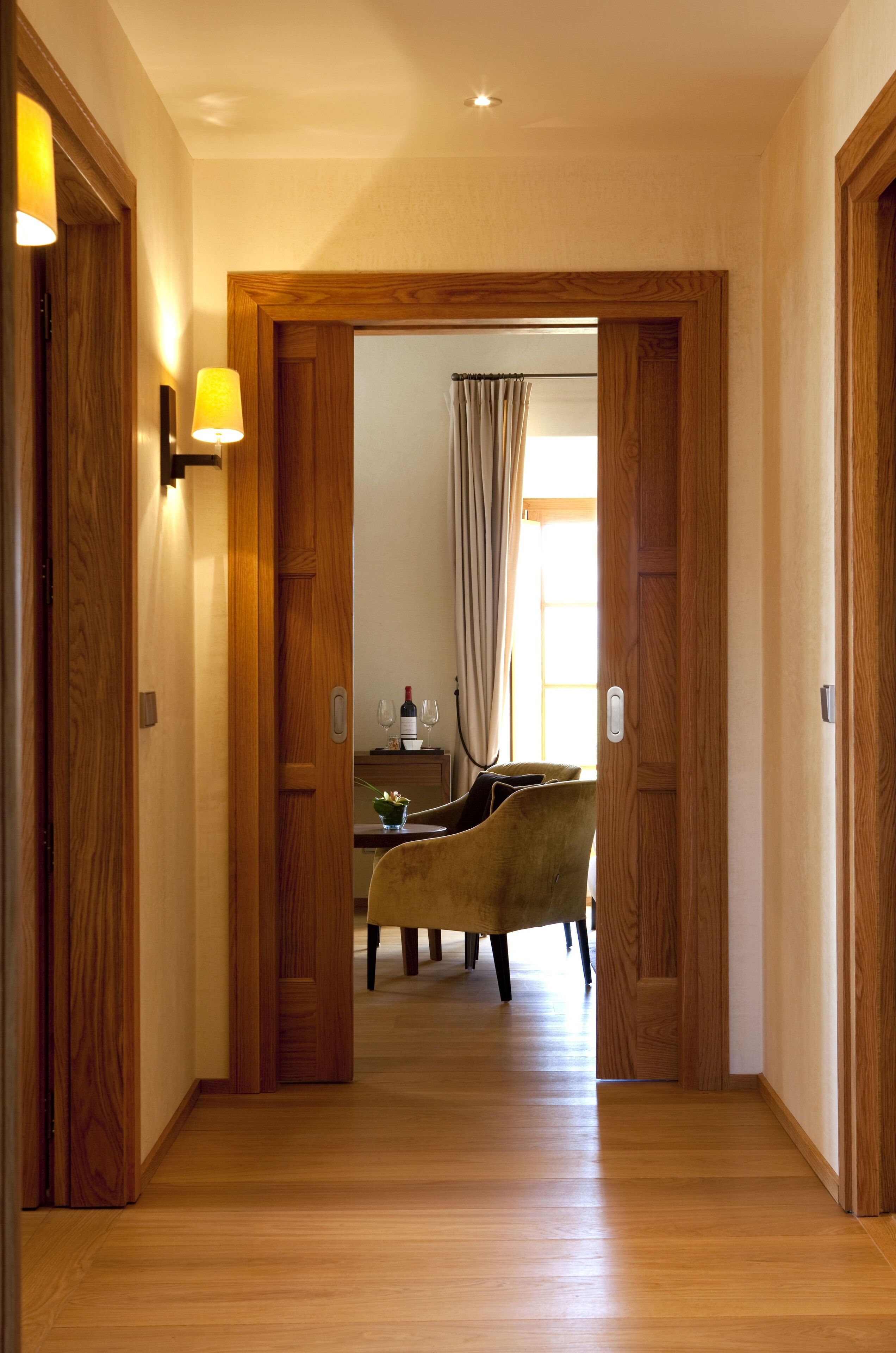 Un corridoio con porte in legno e un'area pranzo con tavolo e sedie.