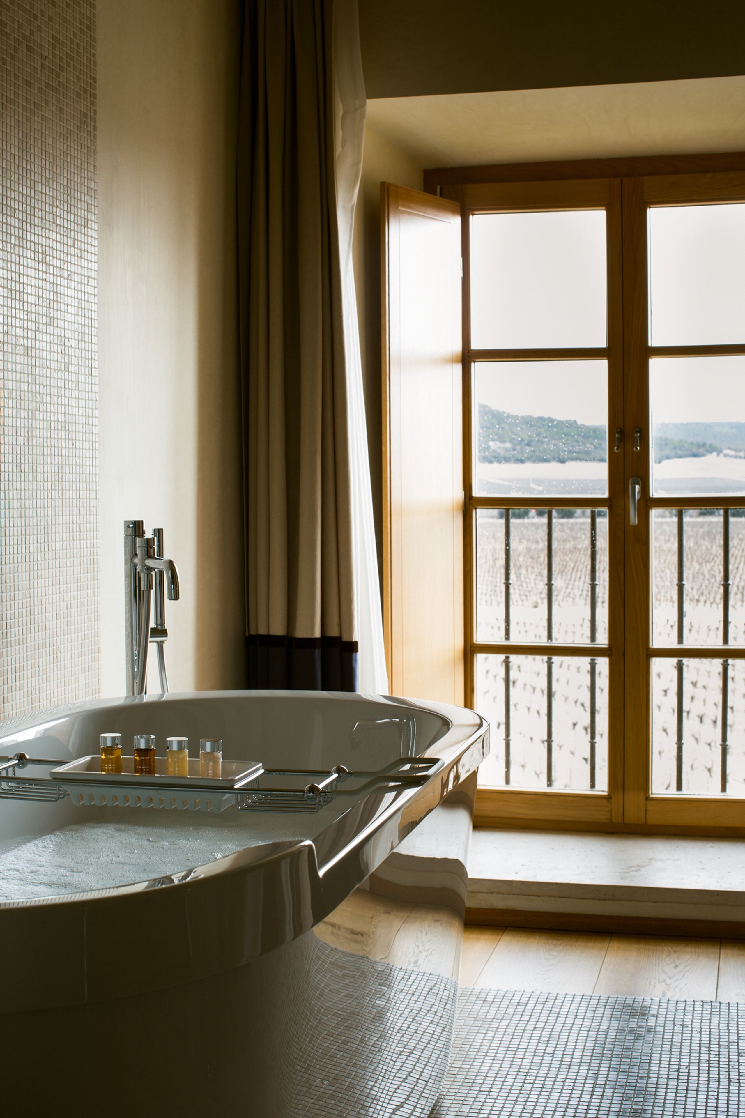 A bathroom with a large bathtub, a shower, and a view of a snowy landscape through a glass door.