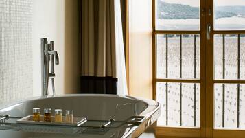 A bathroom with a large bathtub, a shower, and a view of a snowy landscape through a glass door.