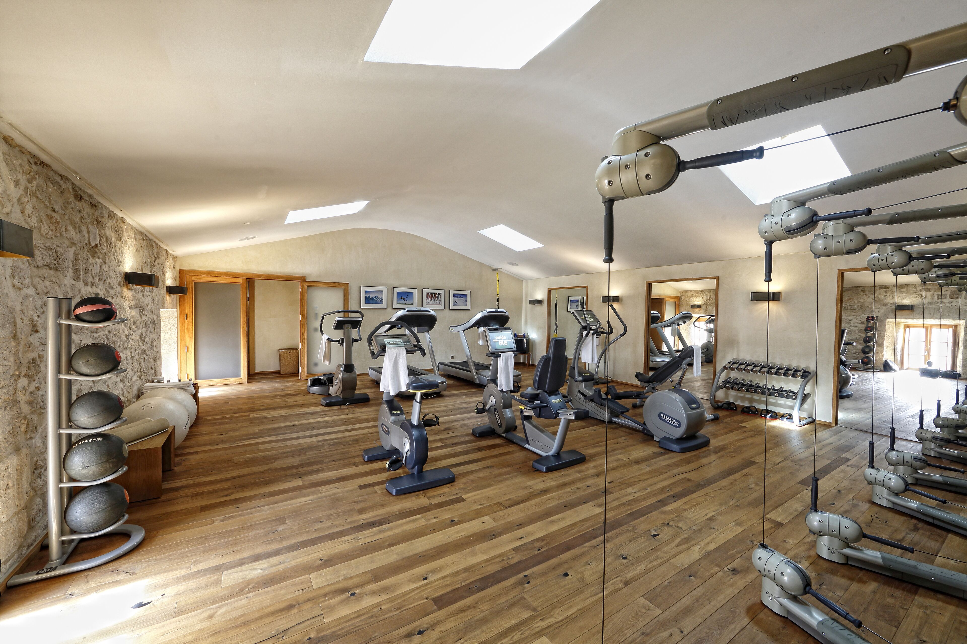 Une salle de sport équipée de divers appareils d’exercice, dotée d’un plancher en bois et d’une verrière.