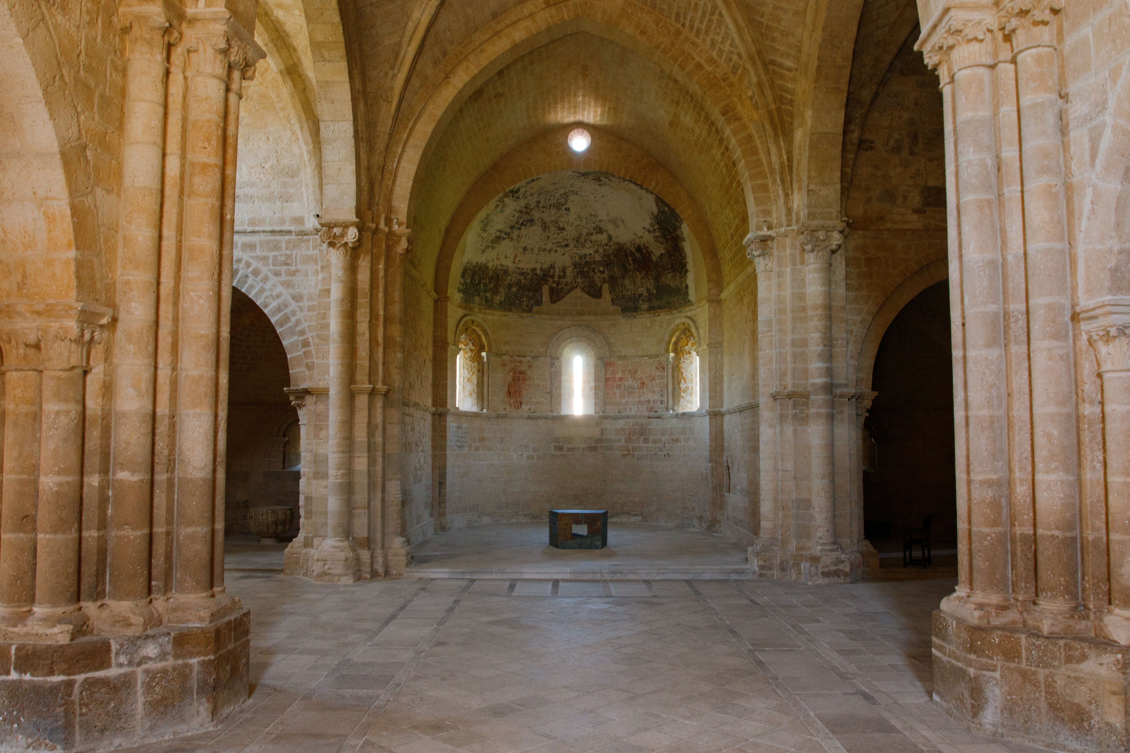 An interior with arched ceilings, stone columns, and a central altar.