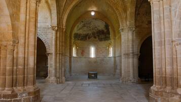 An interior with arched ceilings, stone columns, and a central altar.