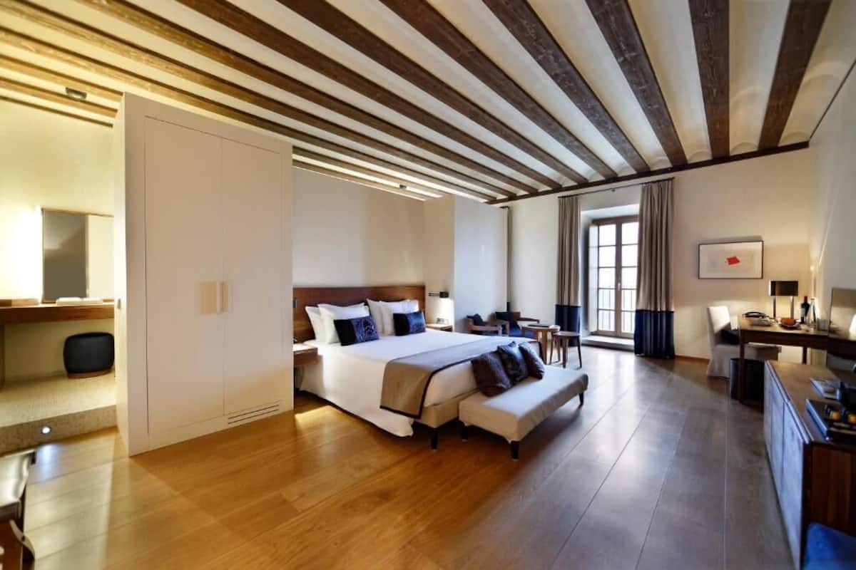Ein geräumiges Hotelzimmer mit einem großen Bett, einem Schreibtisch und einem Sessel.