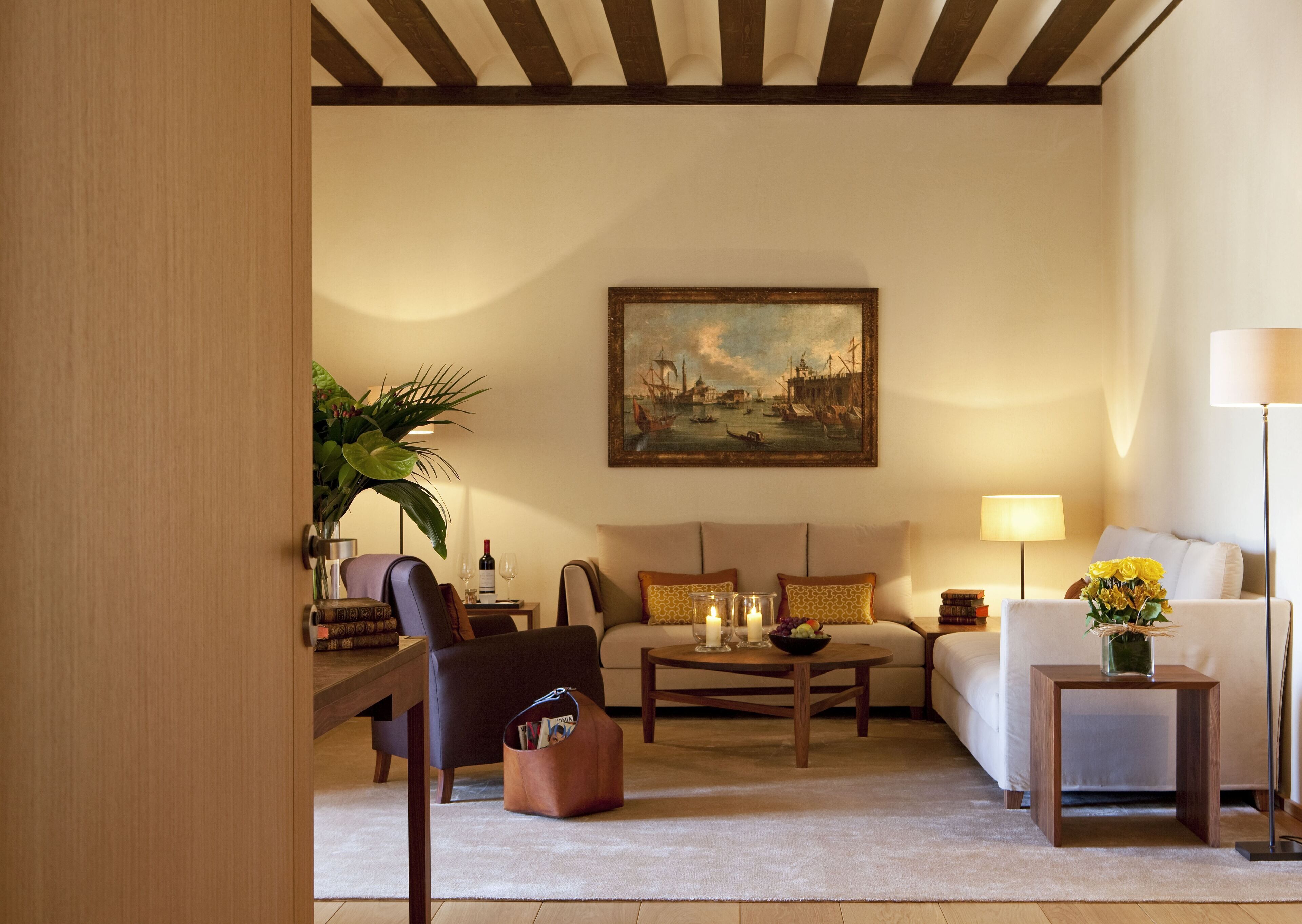 Una sala de estar con un sofá, sillones, una mesa de centro y un cuadro en la pared.