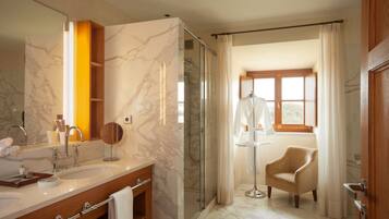 Une salle de bain moderne avec un meuble-lavabo en marbre, une douche à parois de verre et une vue sur un espace extérieur ensoleillé.