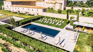 Un grand bâtiment doté d’une piscine, de chaises longues et d’un jardin bien entretenu.