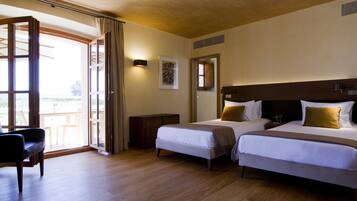 Ein Hotelzimmer mit zwei Betten, einem Schreibtisch und einem großen Fenster mit Vorhängen.