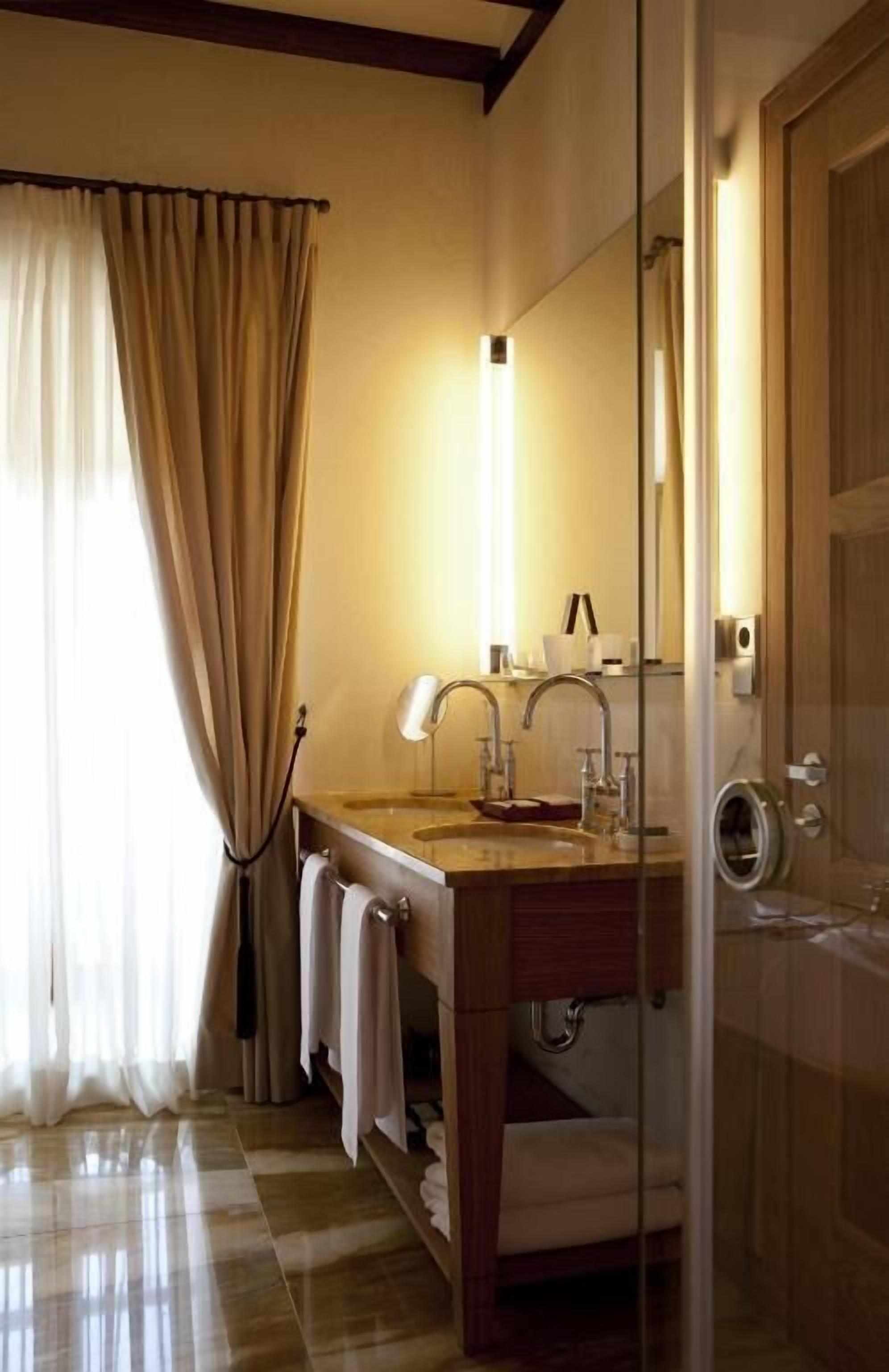 A bathroom with a wooden vanity, a glass shower enclosure, and a large mirror.