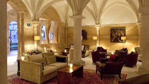 Un hall d’entrée doté de hauts plafonds en arc de cercle, de colonnes en pierre et d’un assortiment de différents types de sièges, notamment des canapés et des fauteuils.
