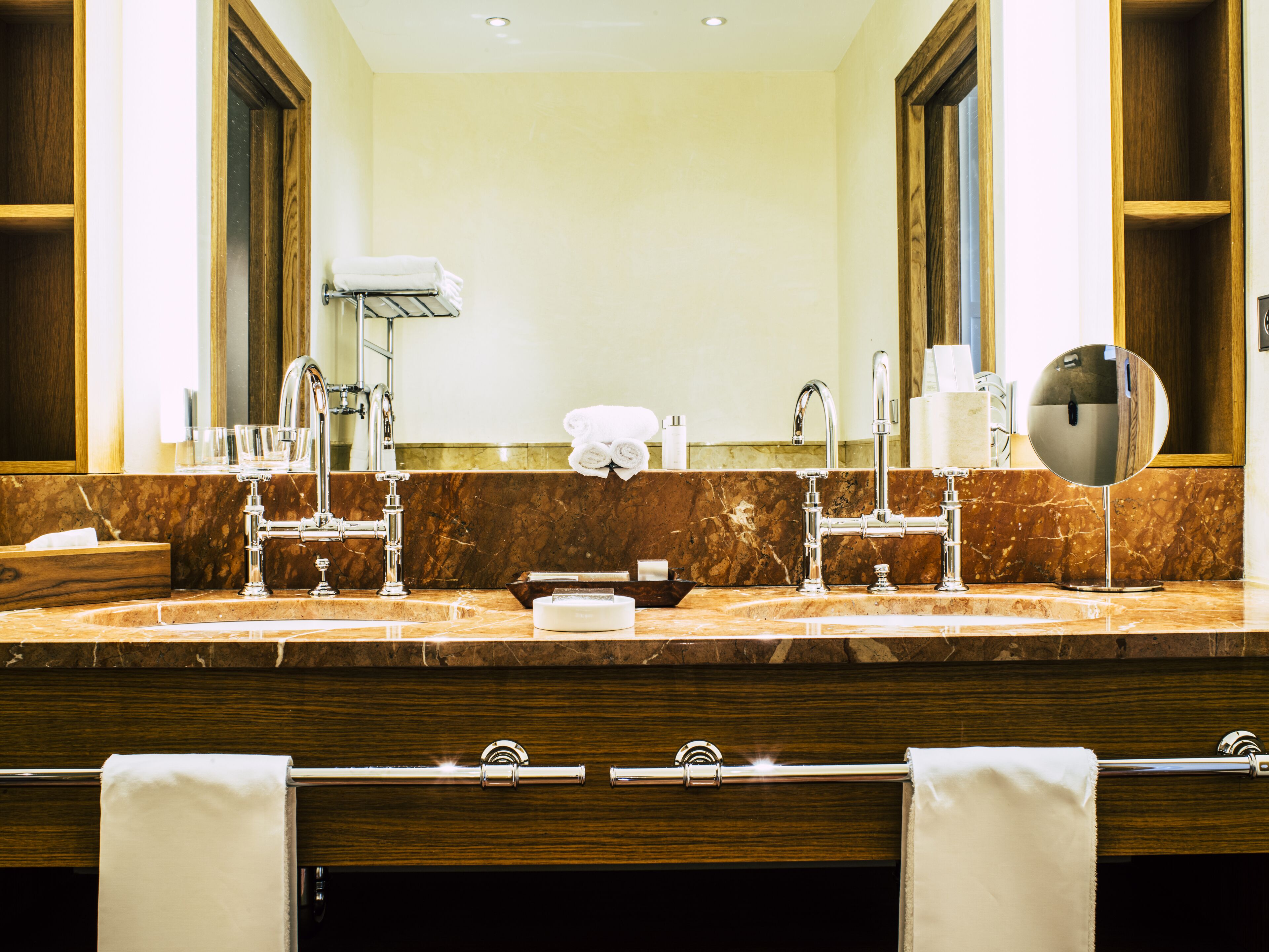A bathroom with a double sink, large mirror, and wooden cabinets.
