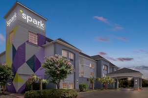 Un hotel de diseño moderno, con un llamativo letrero 'spark by Hilton' y un área de entrada cubierta.