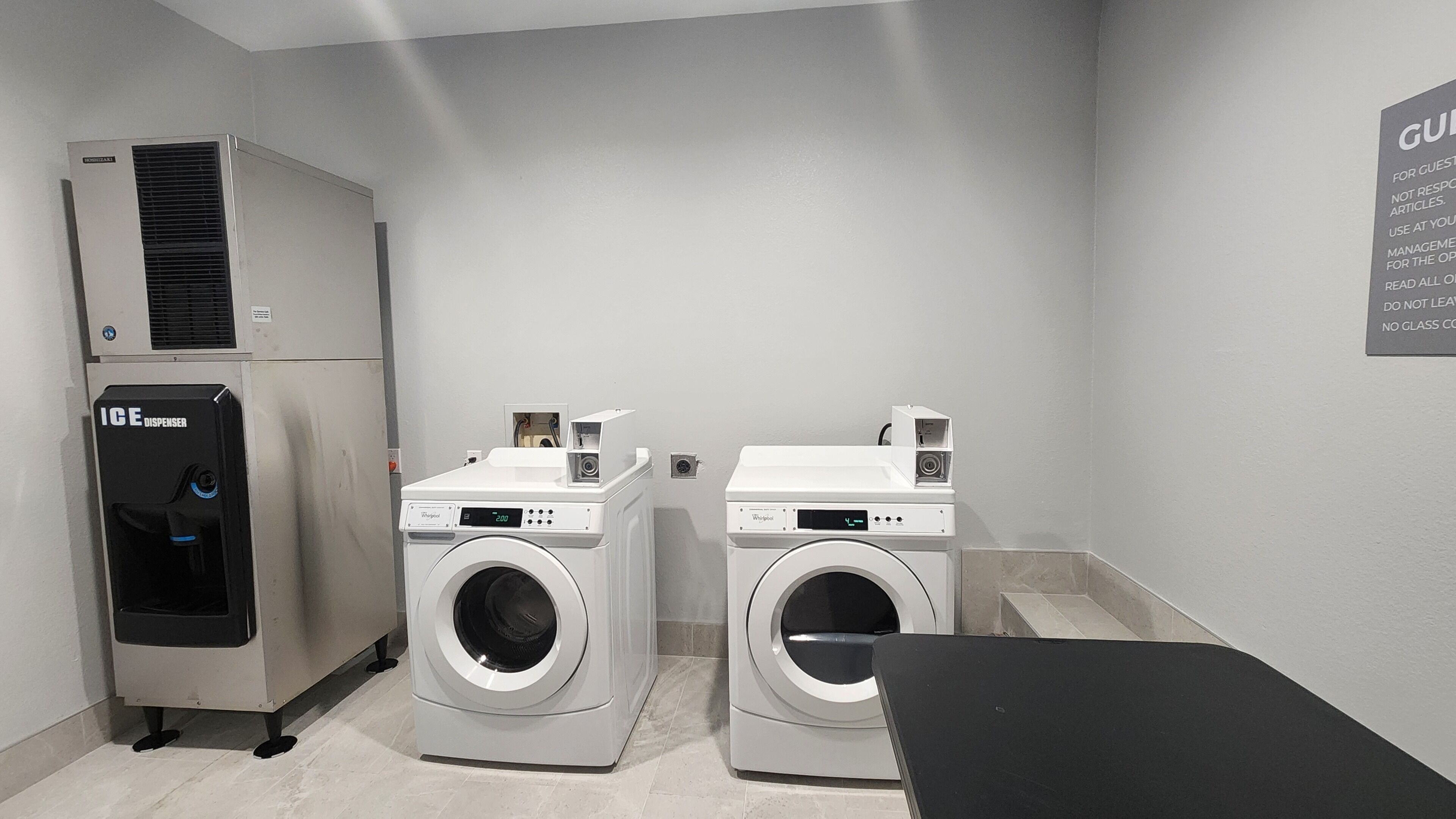 A laundry room with two front-loading washers, a wall-mounted dryer, and an ice dispenser.