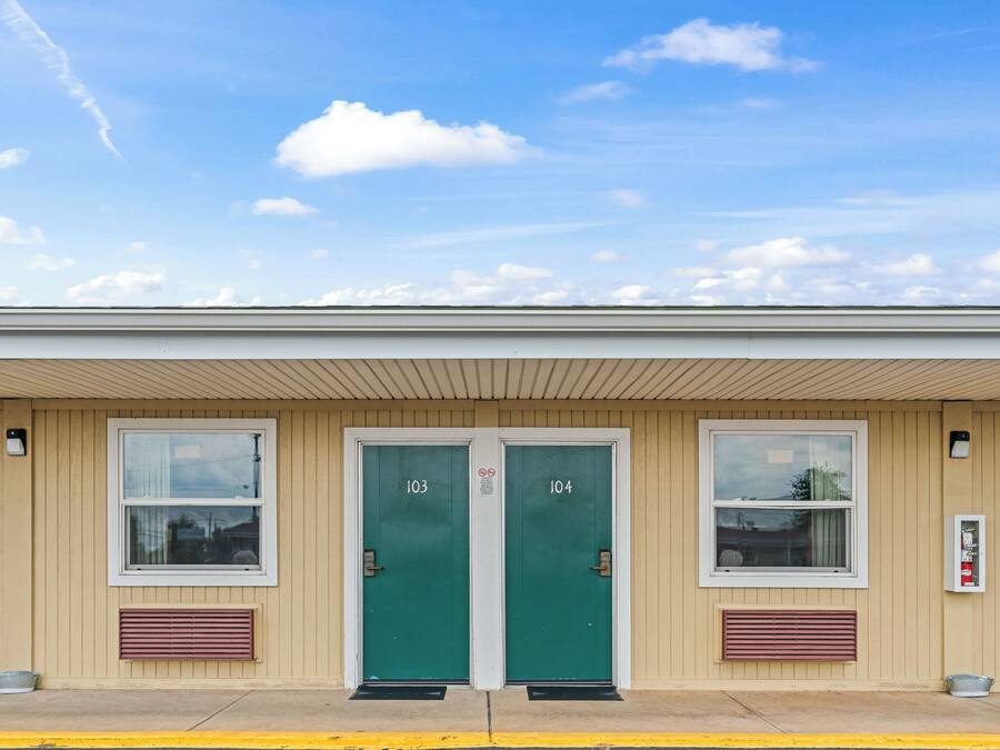 A building with two green doors labeled 103 and 104, a window, and a fire alarm box.