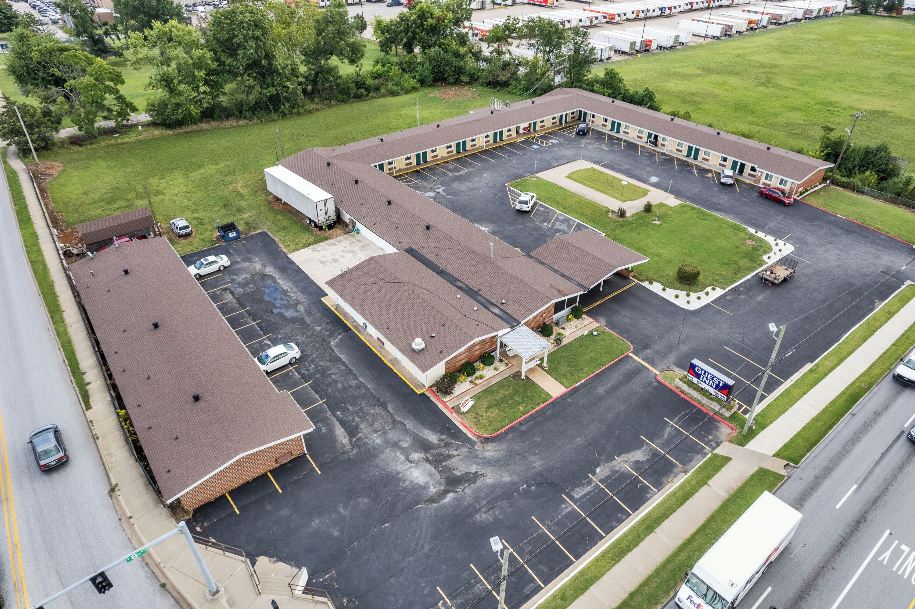 An aerial view of a motel with multiple parking spaces, a central courtyard, and a guest service area.