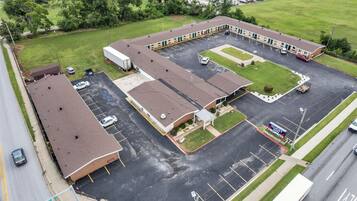 An aerial view of a motel with multiple parking spaces, a central courtyard, and a guest service area.