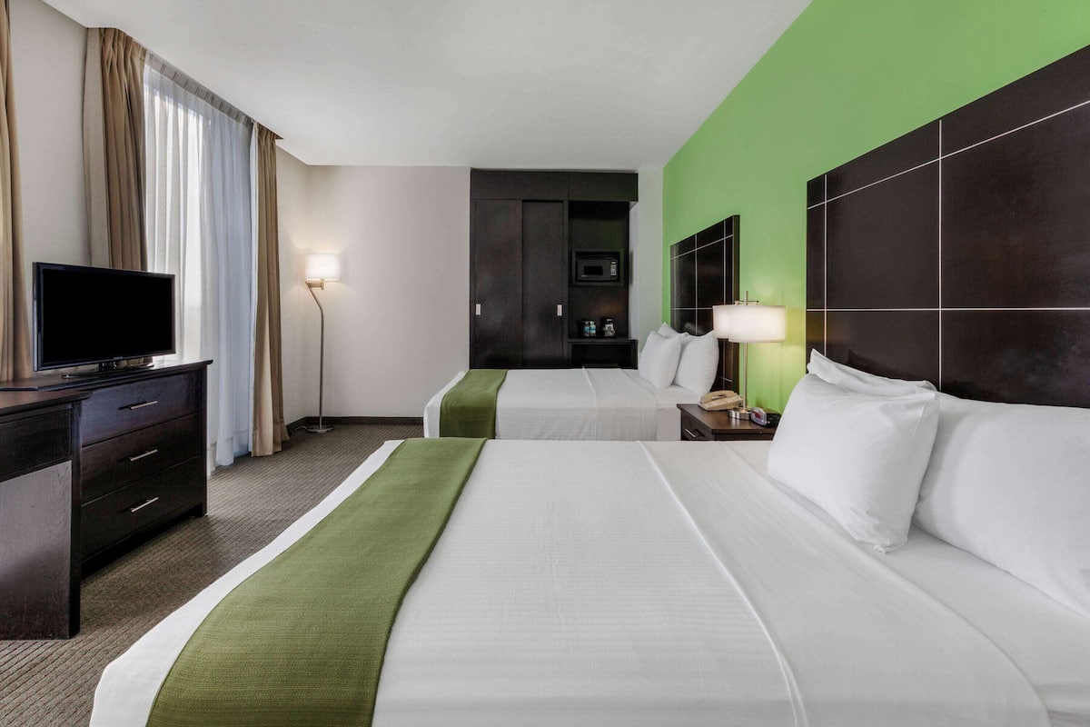 Une chambre d’hôtel avec deux lits, une télévision, un bureau et un mini-bar.