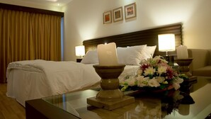 Una camera d'albergo con un letto rifatto, due lampade ai comodini, un vaso di fiori su un tavolo e un quadro appeso al muro.