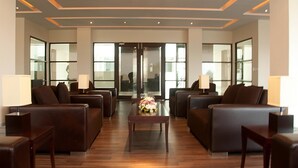 A spacious lobby with leather sofas, a central coffee table, and lamps.
