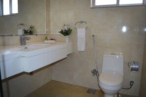 A bathroom with a sink, mirror, toilet, and shower. - Hotel One Down Town (Lahore)