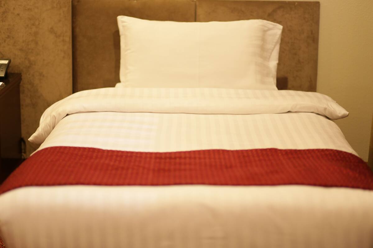 A bed with white bedding and a red blanket.