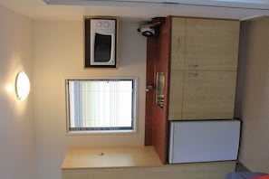 A compact kitchen with a built-in microwave, a small refrigerator, and a window with blinds. - Bella Vista Motel Te Anau (Te Anau)