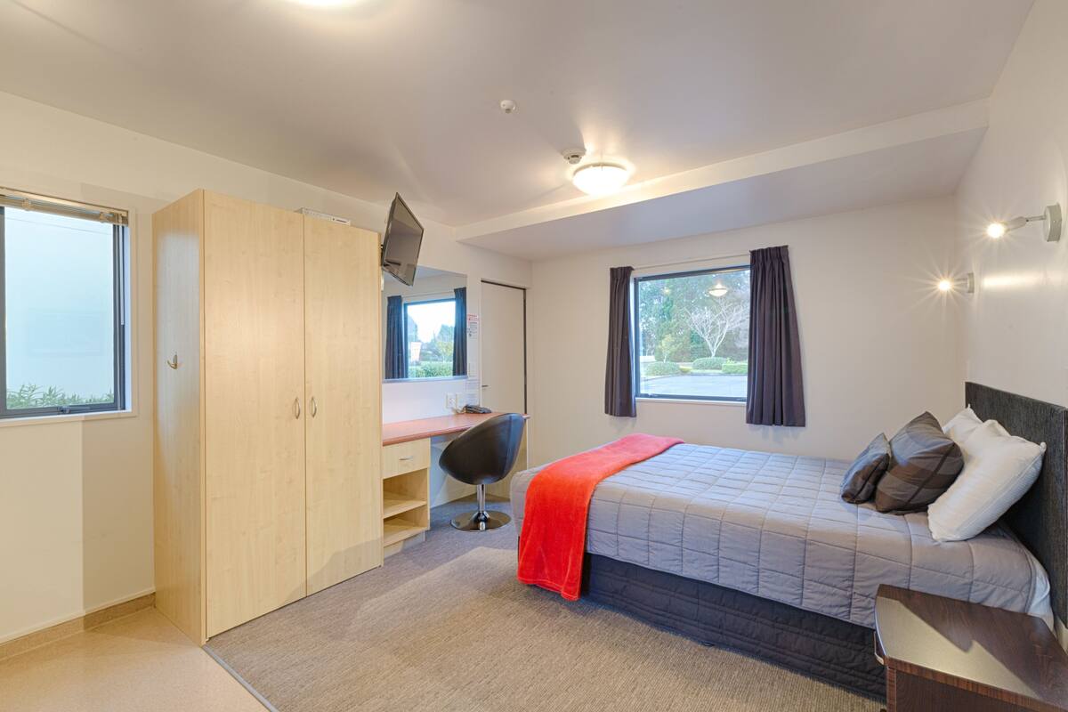 Ein modernes Schlafzimmer mit Bett, Schreibtisch und Kleiderschrank.