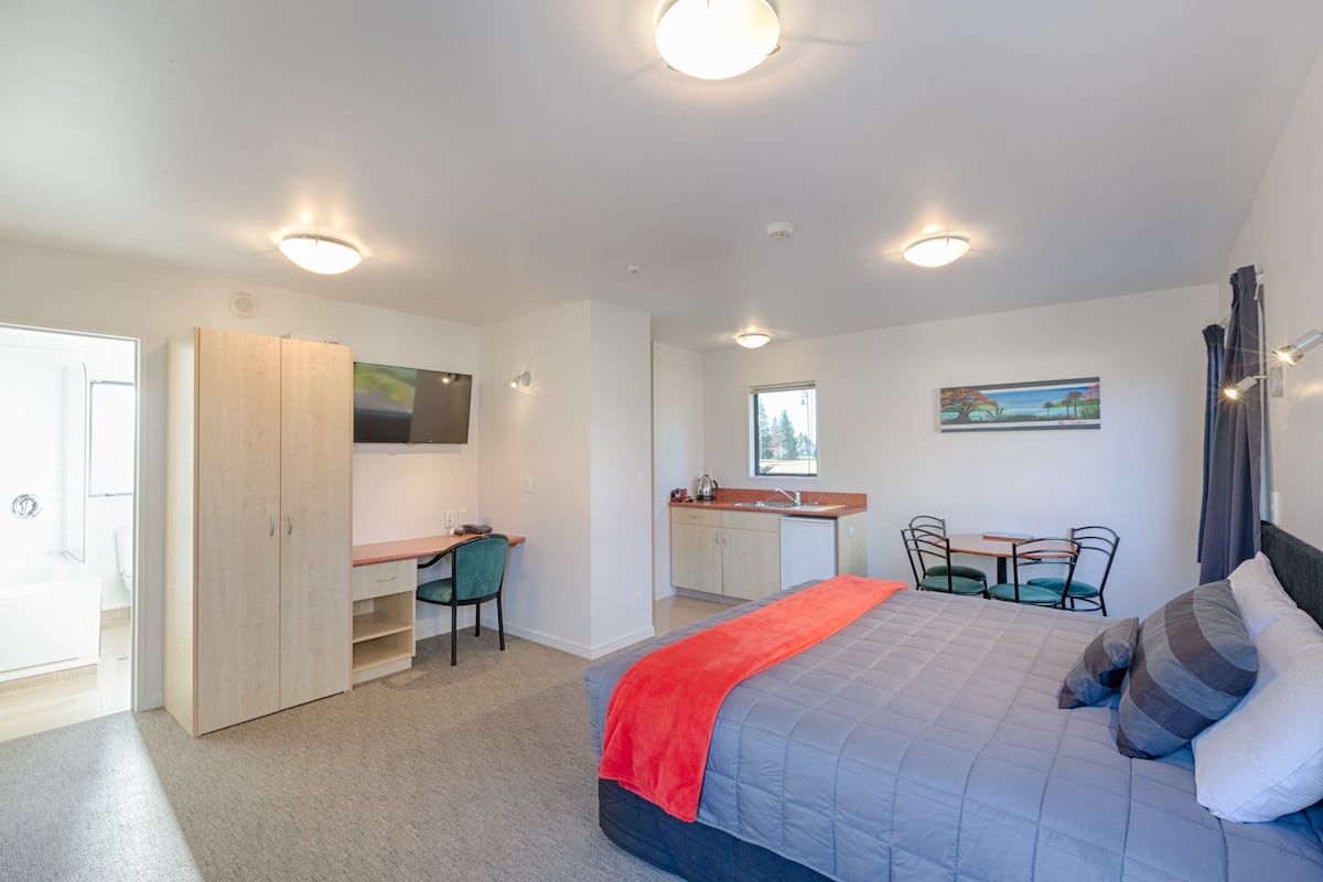 Ein Schlafzimmer mit einem Bett, einem Schreibtisch und einer Küchenzeile.