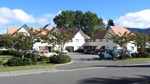 Un motel avec un toit rouge, des murs blancs et plusieurs voitures garées.