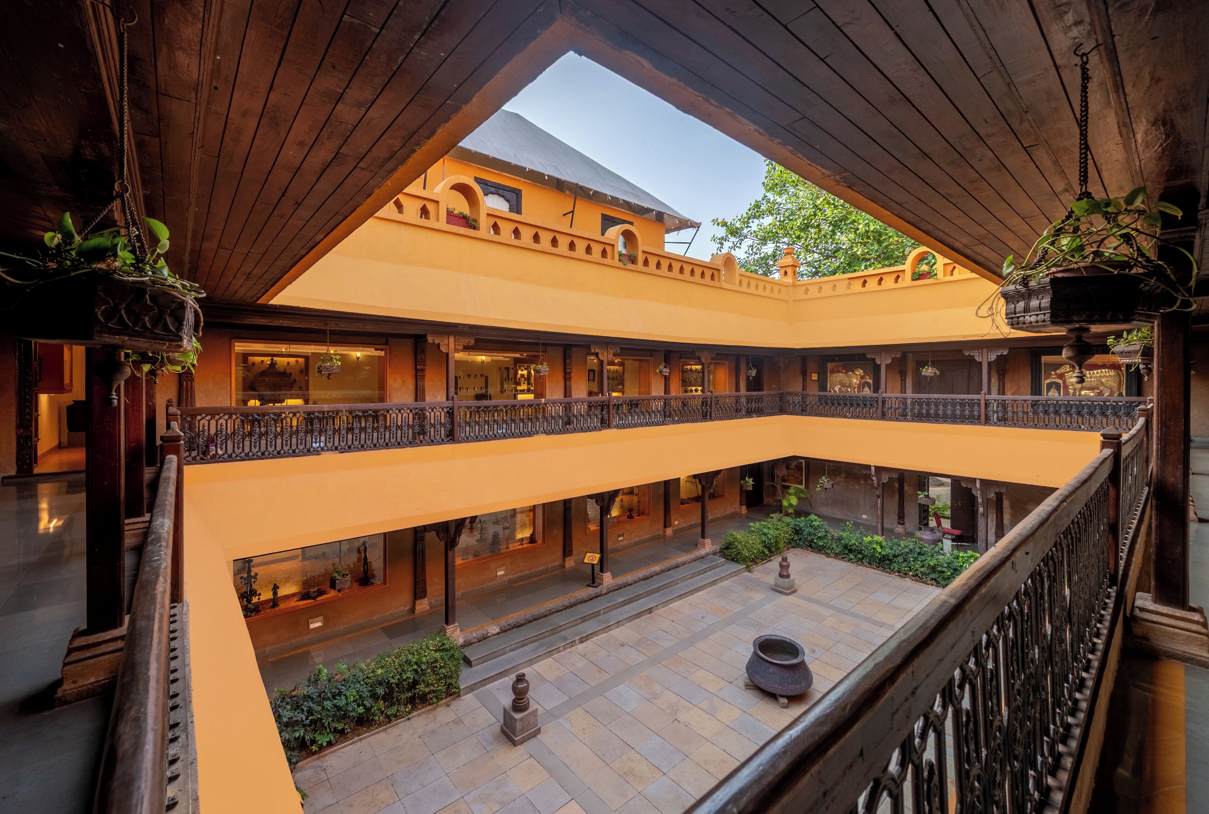 A multi-level courtyard with hanging plants, a central water feature, and traditional architecture.