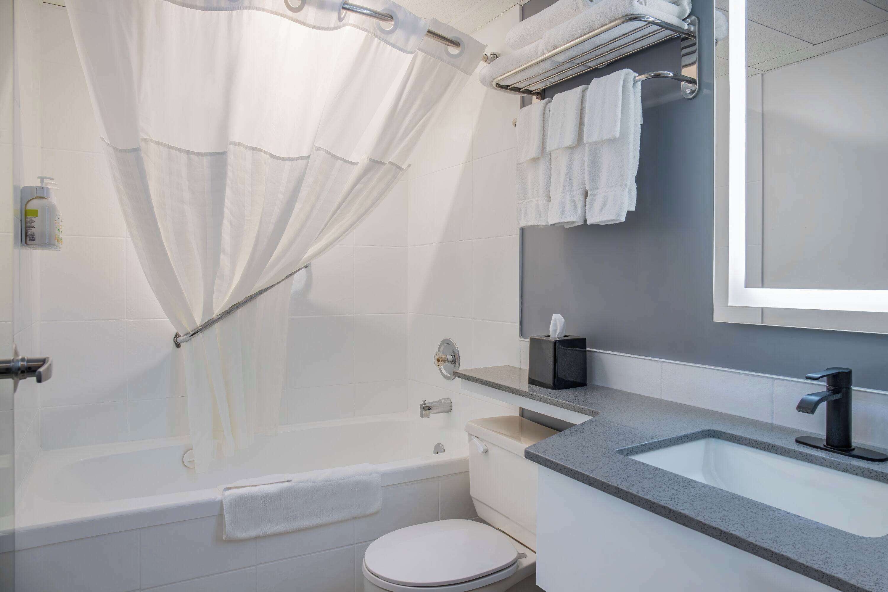 A modern bathroom with a bathtub, toilet, sink, and a shower curtain.
