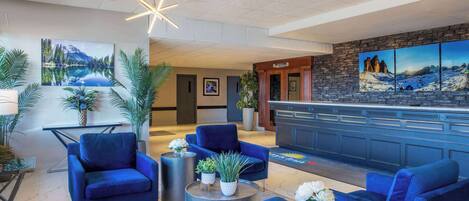A lobby with blue seating, a reception desk, and artwork on the walls.