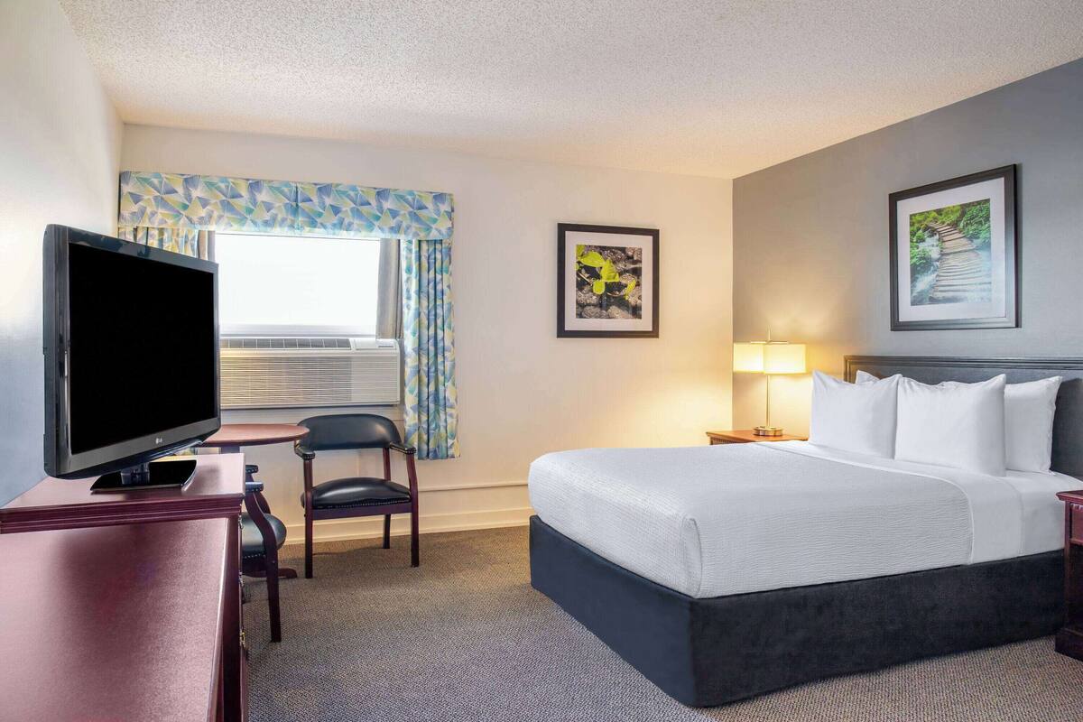 Ein Hotelzimmer mit einem Bett, einem Fernseher, einem Schreibtisch und einem Sessel.