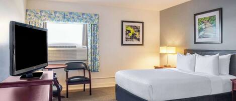 Ein Hotelzimmer mit einem Bett, einem Fernseher, einem Schreibtisch und einem Sessel.