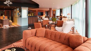 A modern hotel lobby with a seating area, a bar, and a television. - ibis Styles Nantes Saint Herblain (Saint-Herblain)