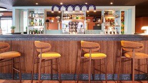 A bar area with a marble countertop, wooden bar stools, and a variety of bottles and glasses. - ibis Styles Nantes Saint Herblain (Saint-Herblain)