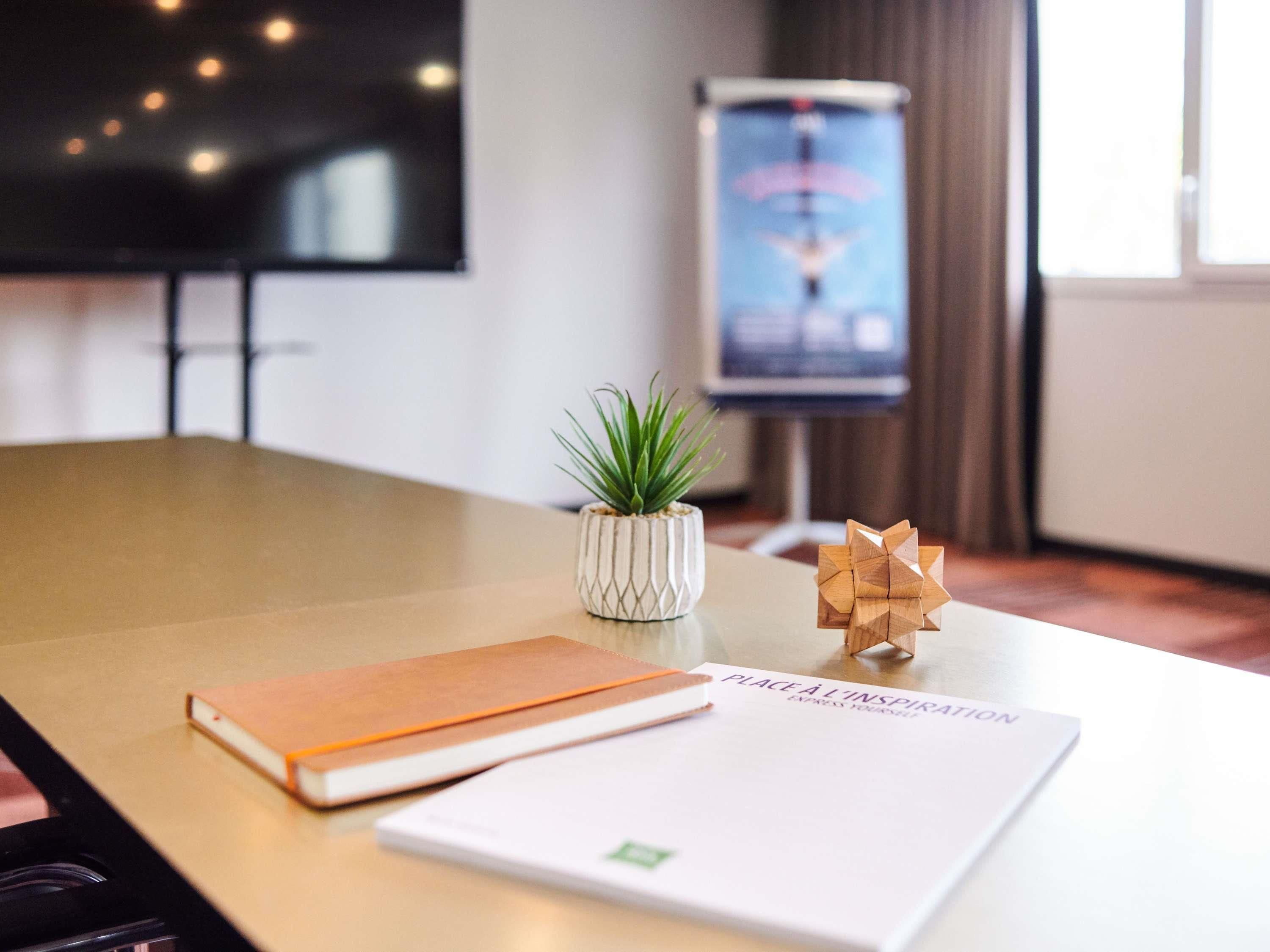 Une table de conférence avec un carnet, une petite plante en pot et un puzzle en bois.