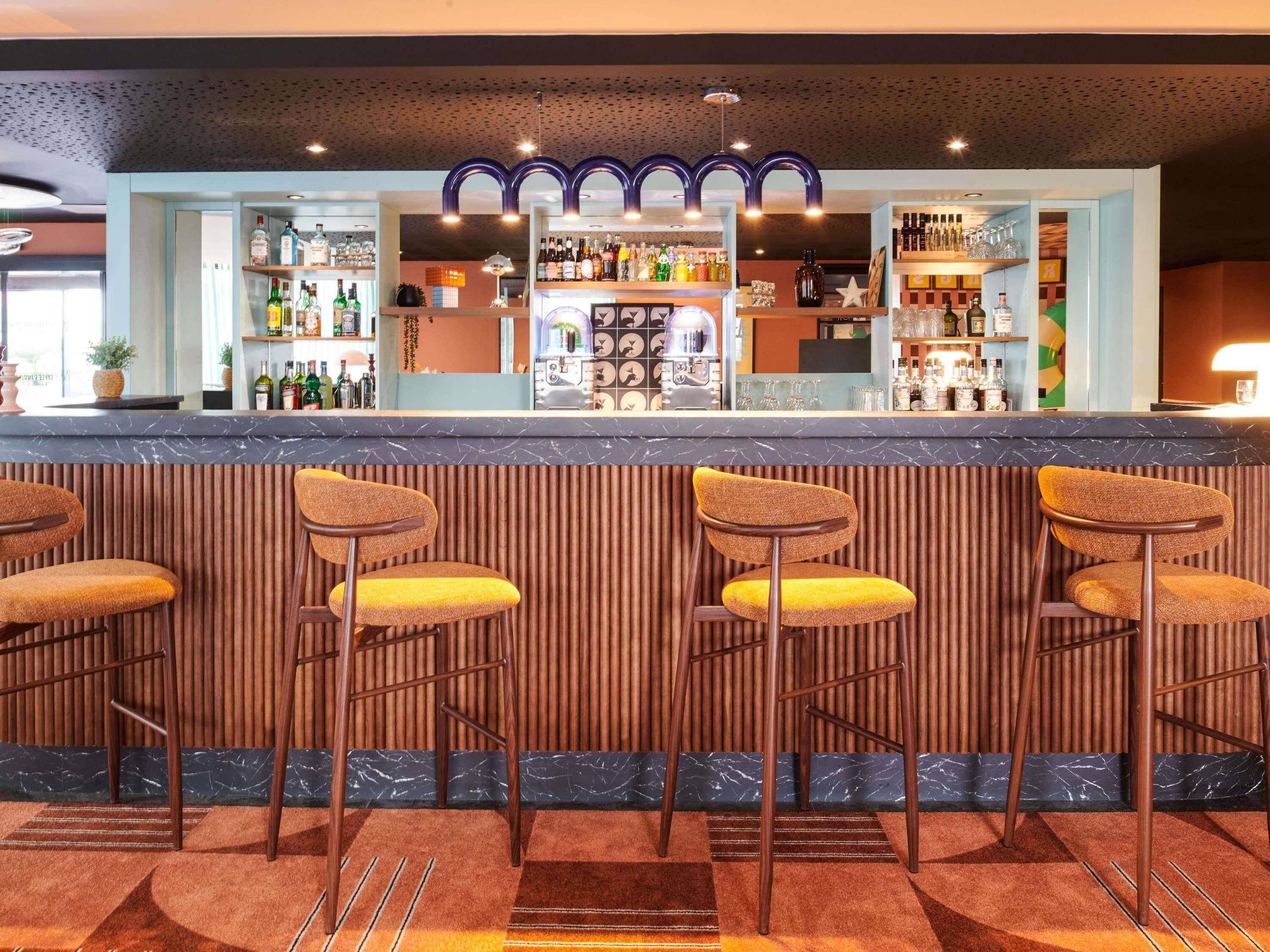 Un espace bar doté d’un comptoir en marbre, de tabourets de bar en bois et d’une variété de bouteilles et de verres.