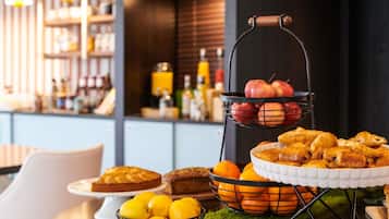 Zona de comedor con barra libre que incluye frutas, pasteles y una tarta.
