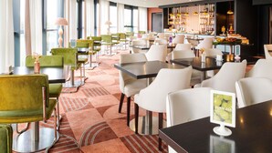 A modern restaurant with a bar area, multiple seating options including booths and tables, and a view of the outdoors through large windows. - ibis Styles Nantes Saint Herblain (Saint-Herblain)