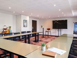Una sala de conferencias con una mesa larga, sillas, un televisor y un cartel en la pared.