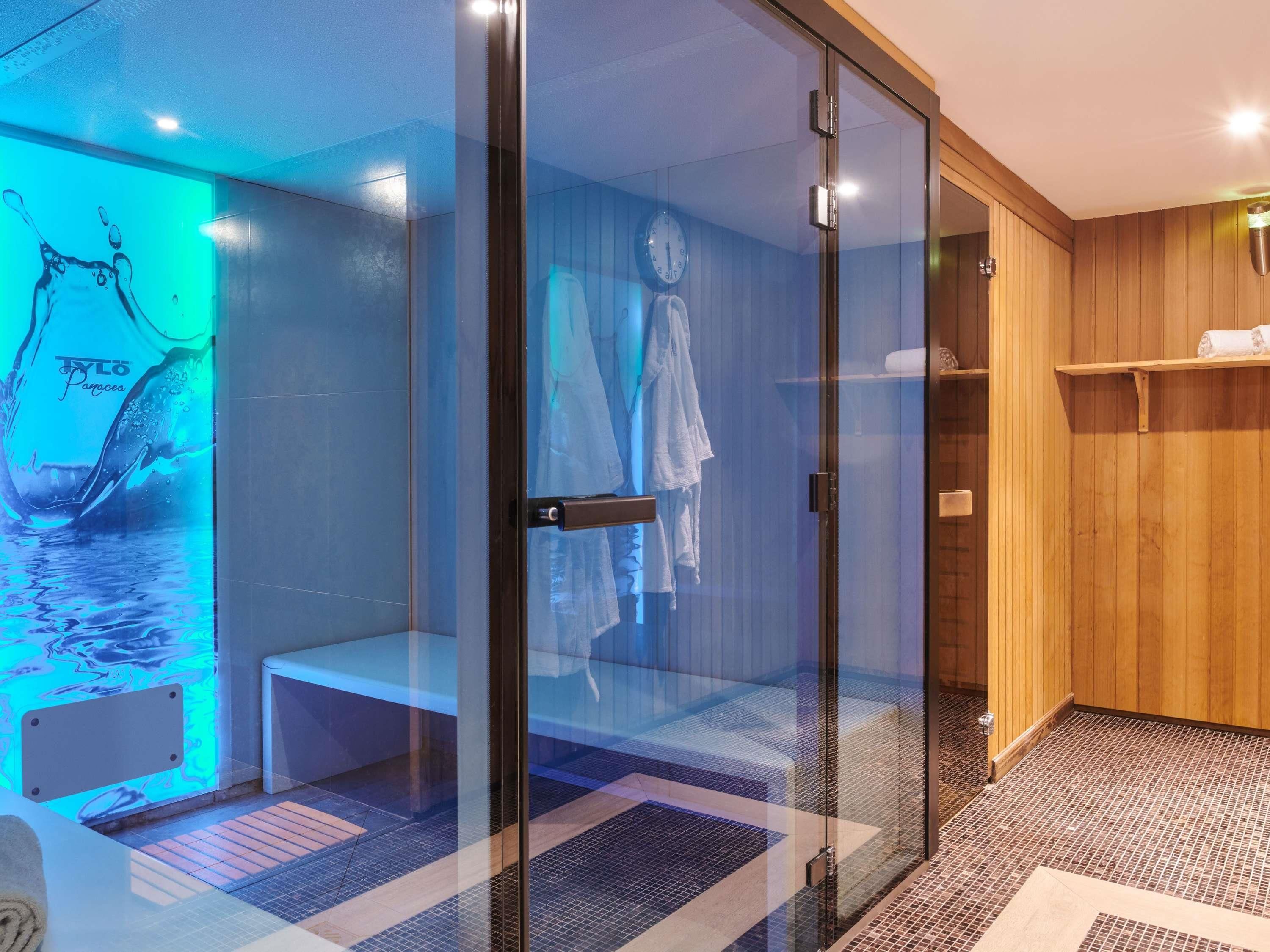 Un sauna entièrement vitré, avec un banc, un mur en bois et un porte-serviettes.