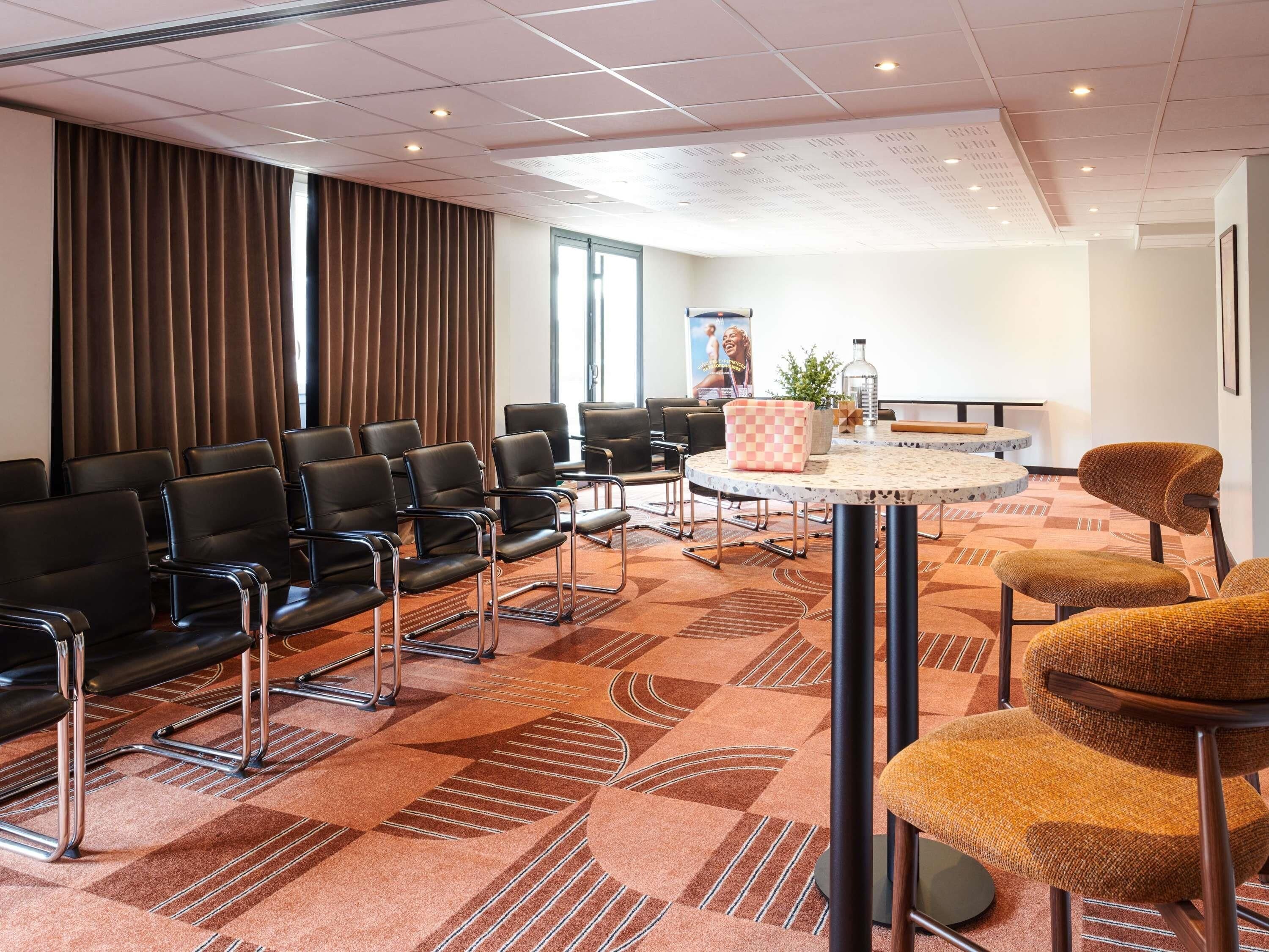A conference room with black chairs, a round table, and a patterned carpet.