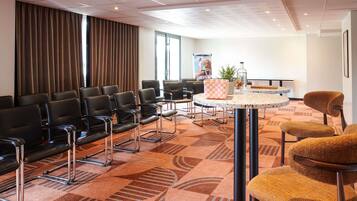 A conference room with black chairs, a round table, and a patterned carpet.