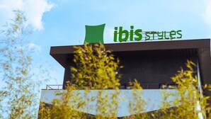 Un edificio con un letrero verde que dice 'ibis styles'.