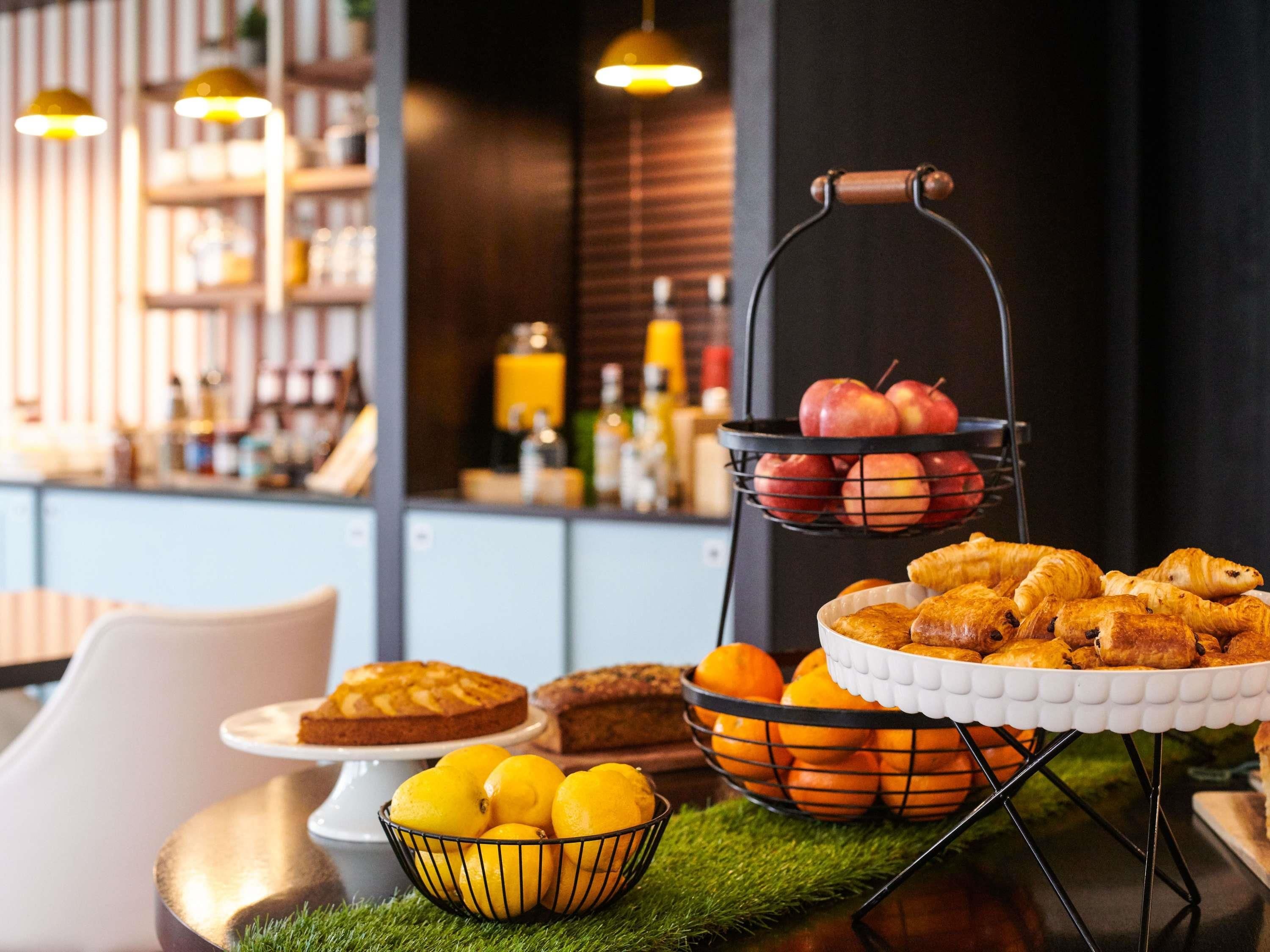 A dining area with a buffet setup including fruits, pastries, and a cake.