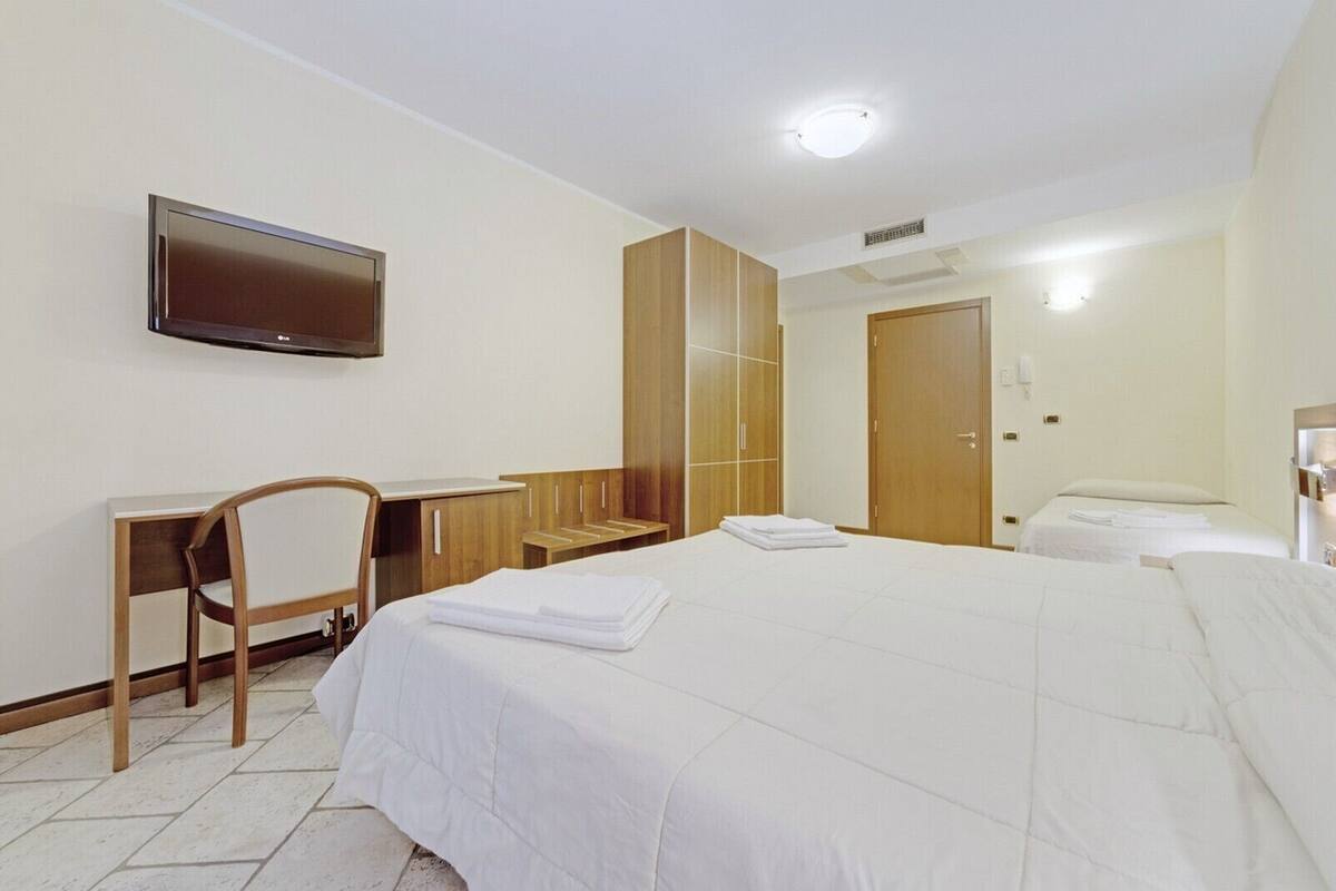 Een hotelkamer met een bed, een bureau, een stoel, een televisie en een kledingkast.