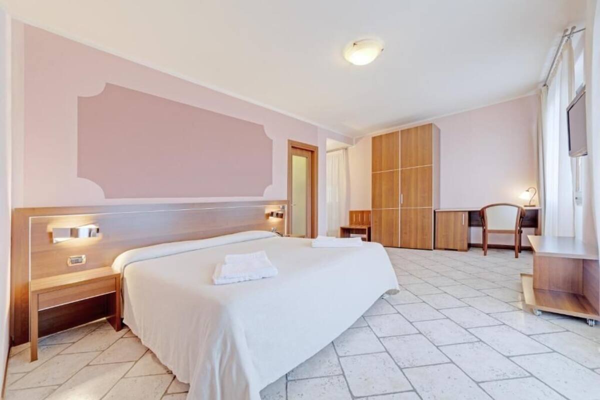 Een hotelkamer met een groot bed, een houten garderobe, een bureau en een stoel.
