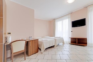 Een hotelkamer met twee bedden, een bureau, een stoel, een televisie en een minibar.