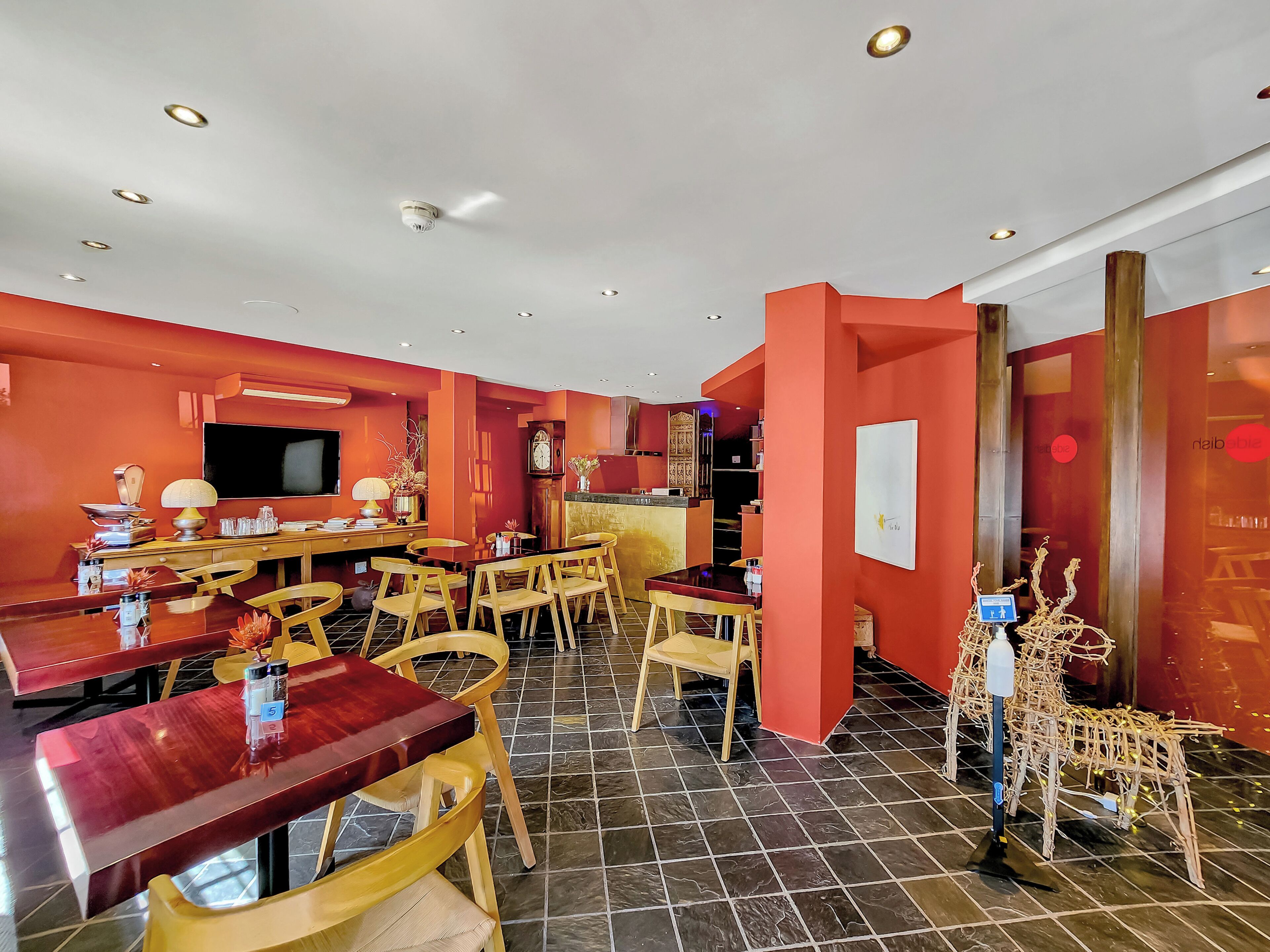 A dining area with a red wall, wooden furniture, and a tiled floor.