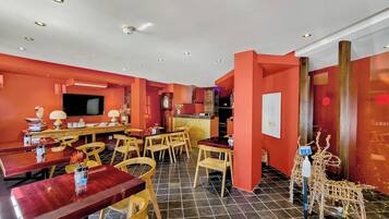 A dining area with a red wall, wooden furniture, and a tiled floor.